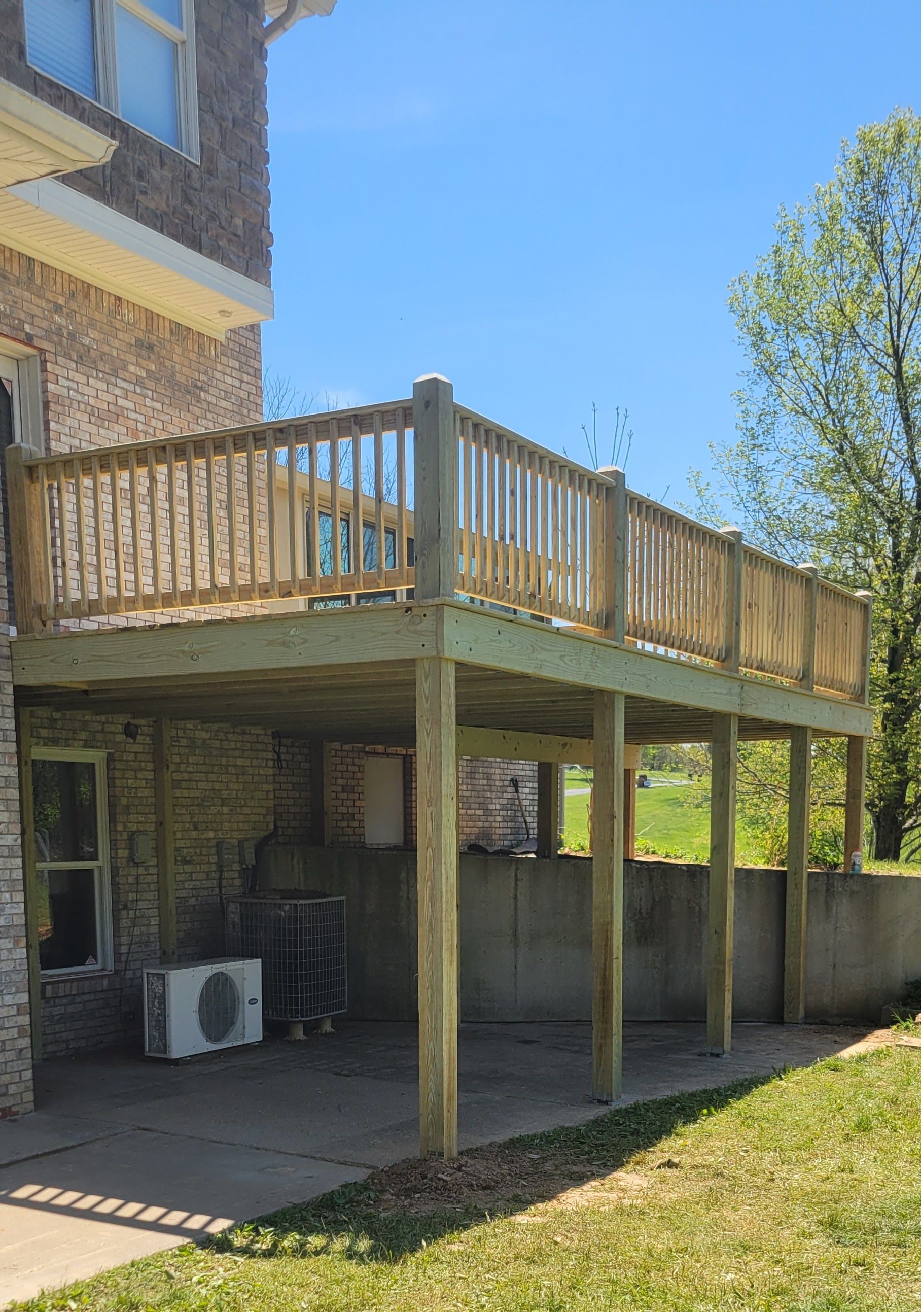 A wooden deck is sitting in the backyard of a house.