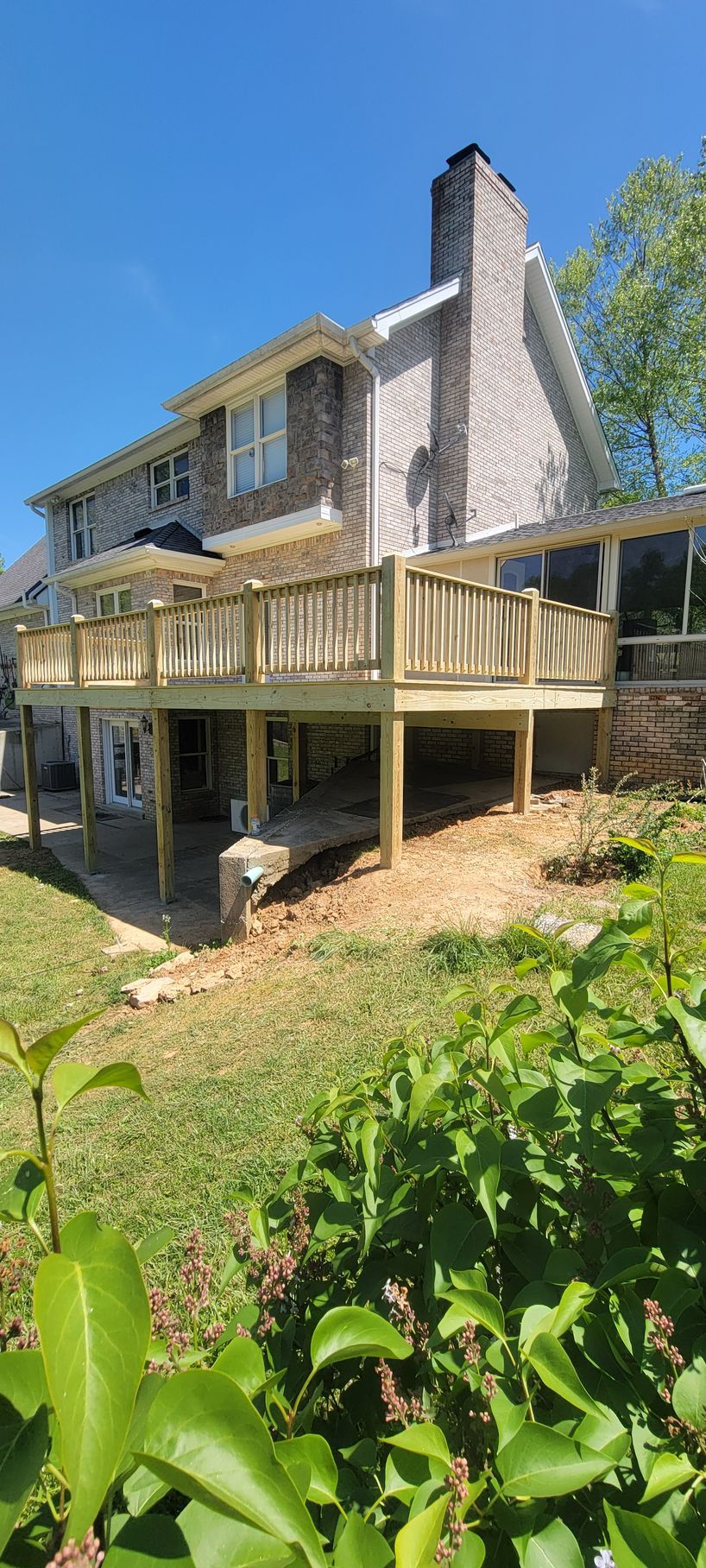 A large wooden deck is sitting in front of a large brick house.