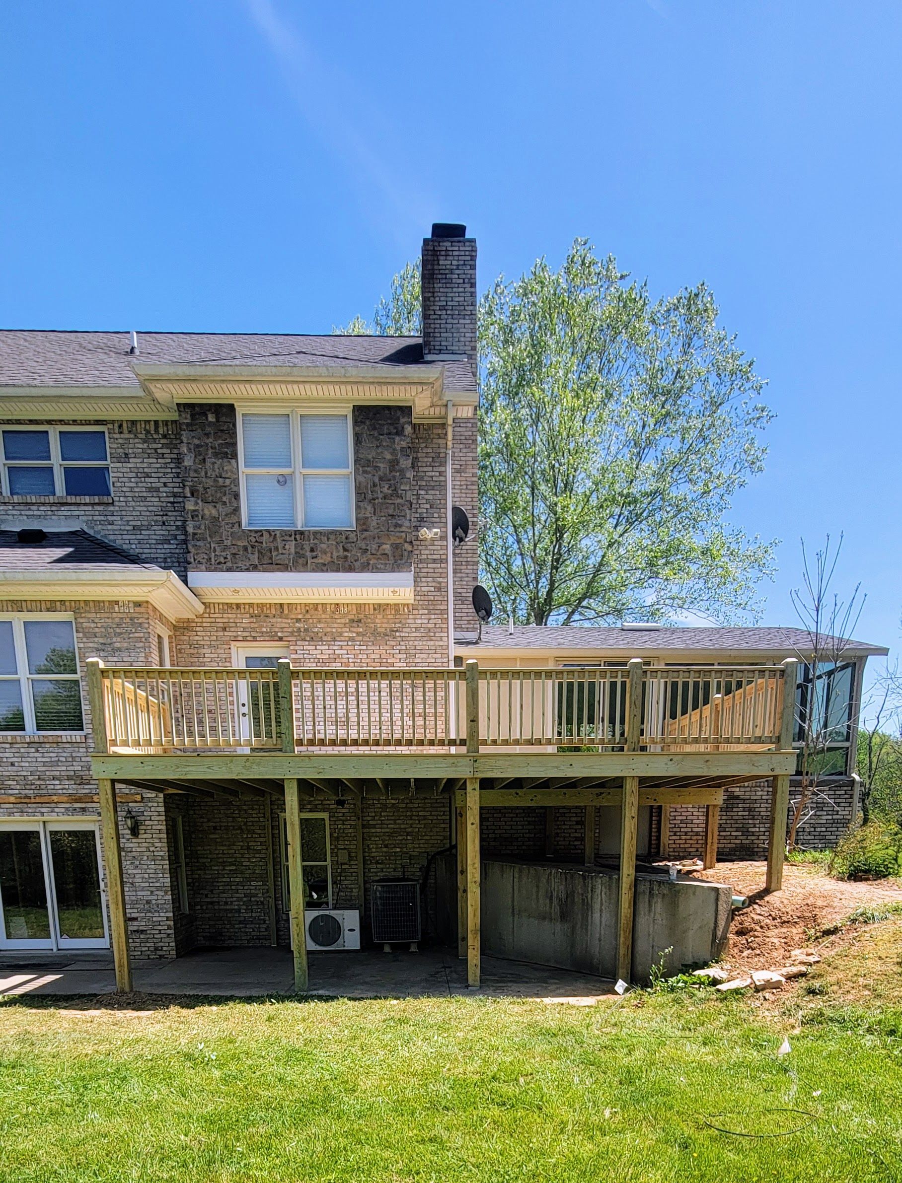 The back of a house with a large deck and a chimney.