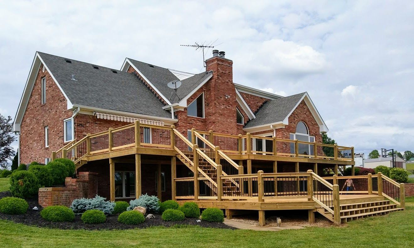 A large brick house with a large wooden deck in front of it.