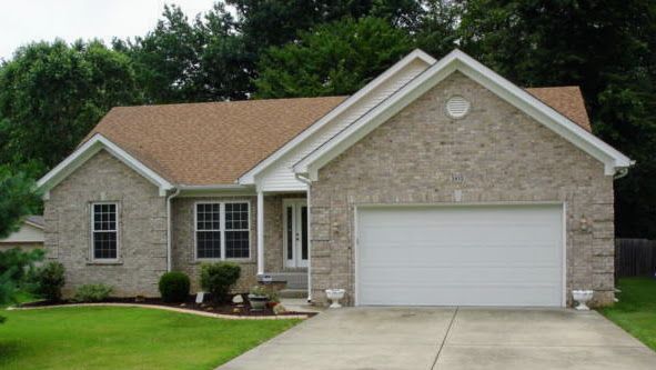 A brick house with a brown roof and a white garage door