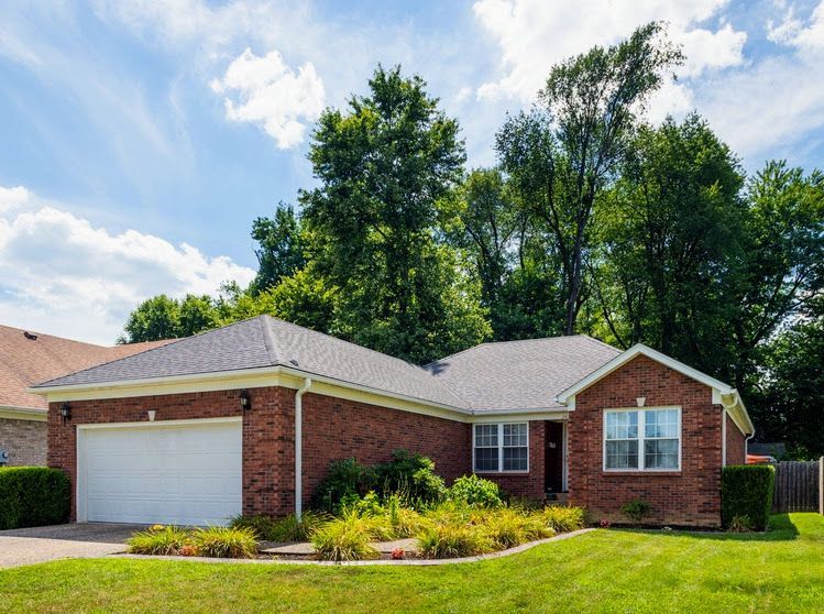 A brick house with a white garage door and trees in the background