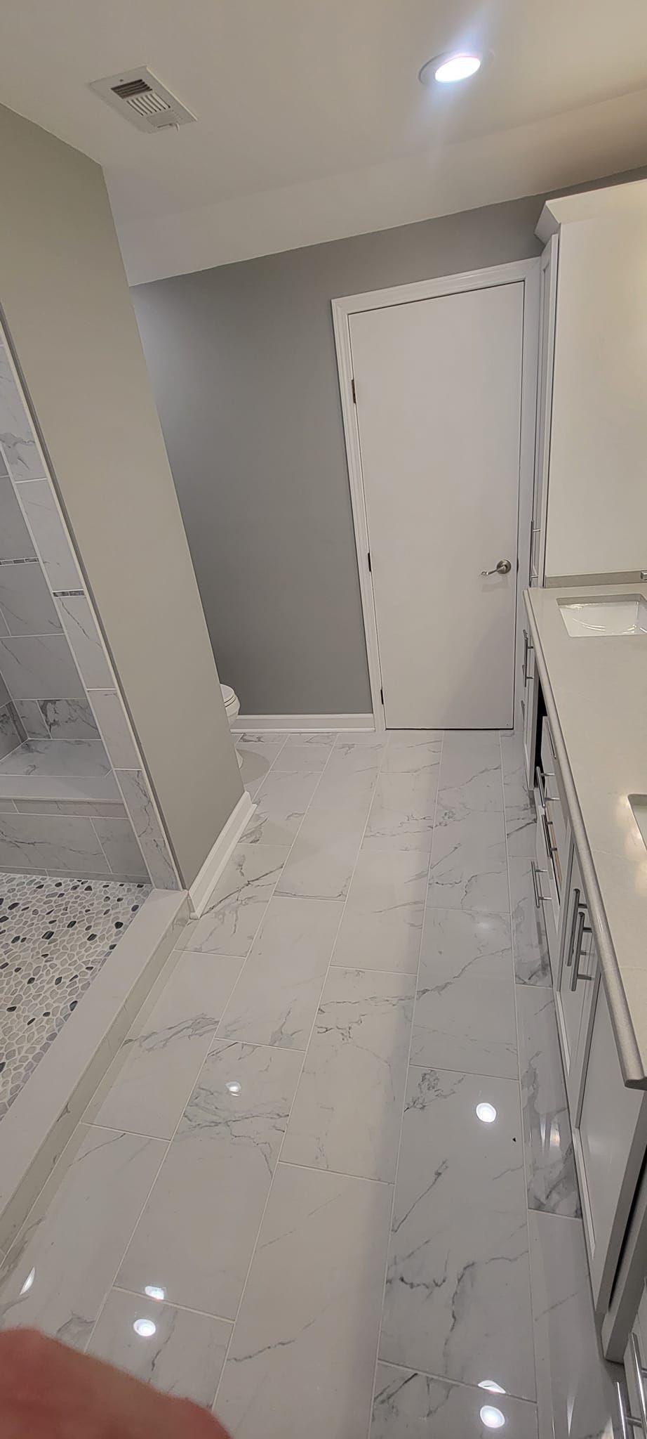 A person is standing in a bathroom with a marble floor.