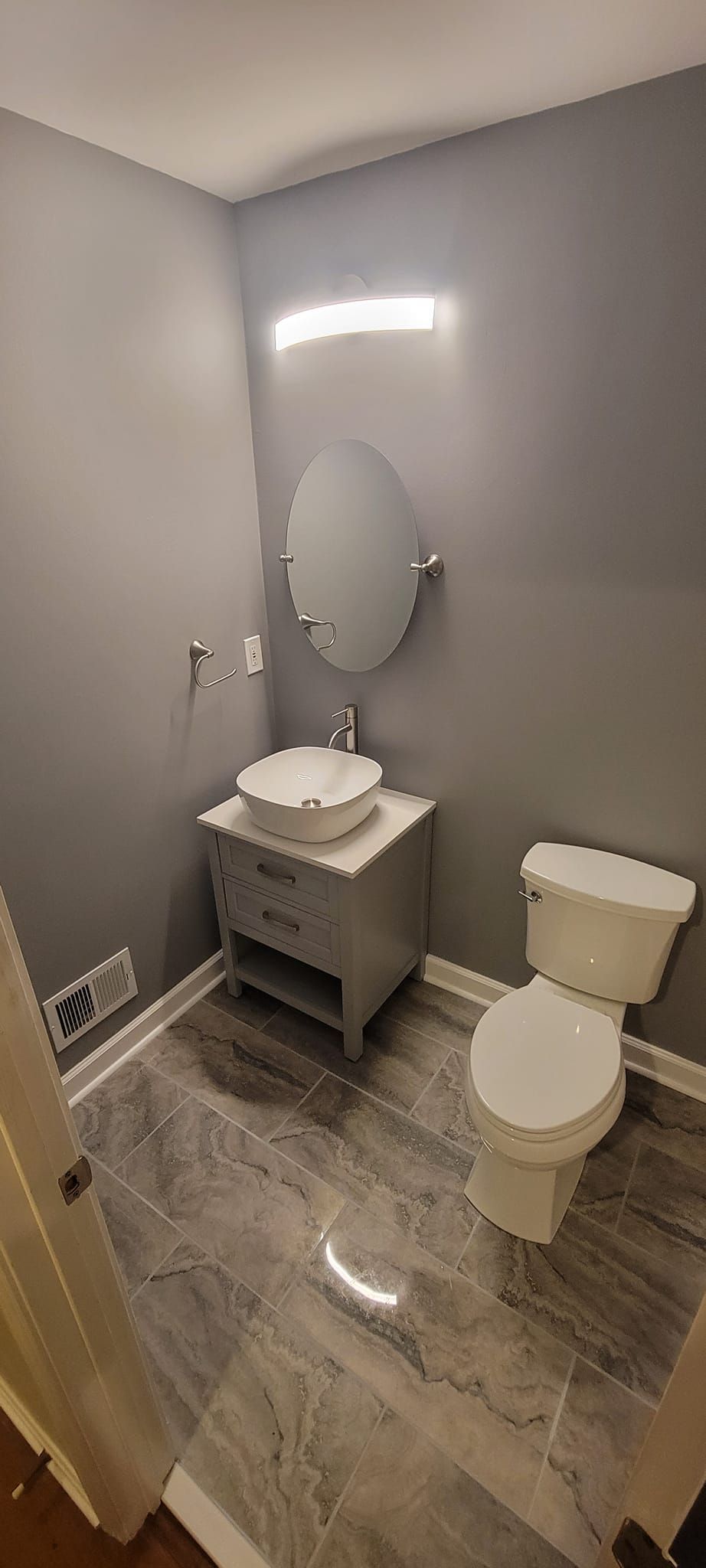 A bathroom with a toilet , sink and mirror.