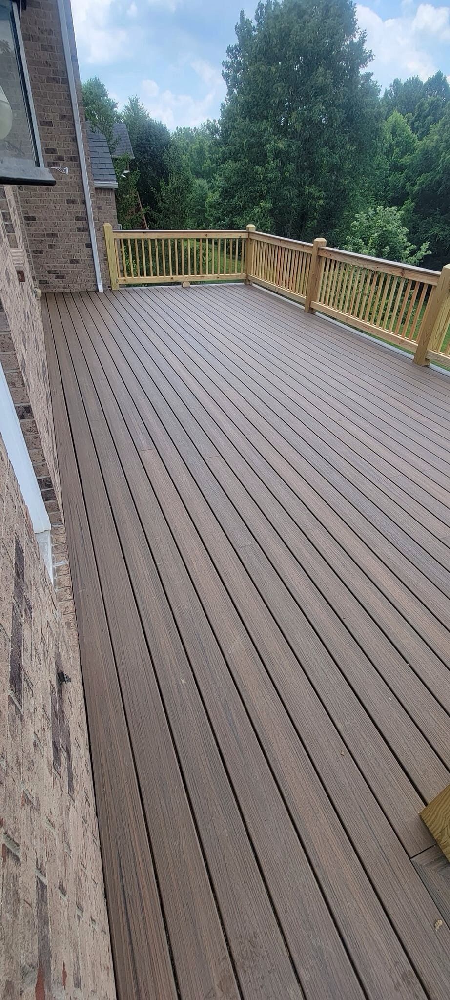 A wooden deck with a wooden railing and trees in the background.