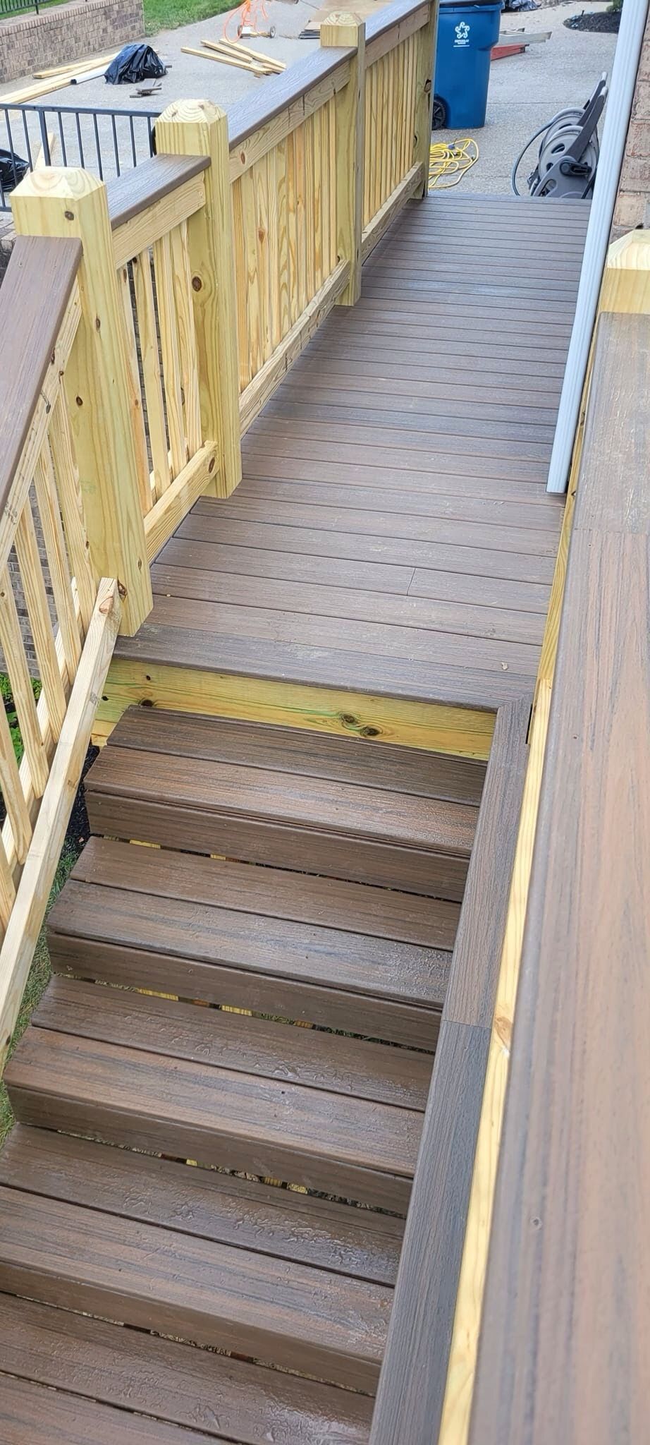 A wooden deck with stairs and a yellow railing.