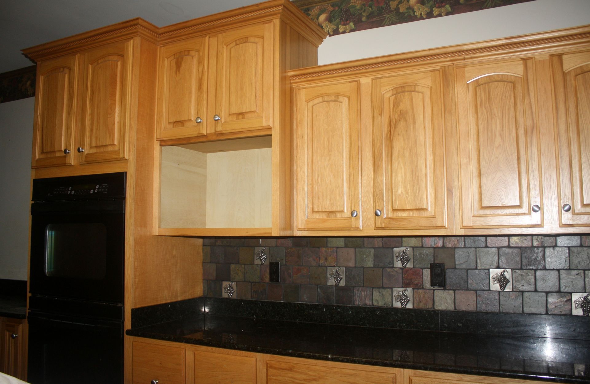A kitchen with wooden cabinets and black counter tops