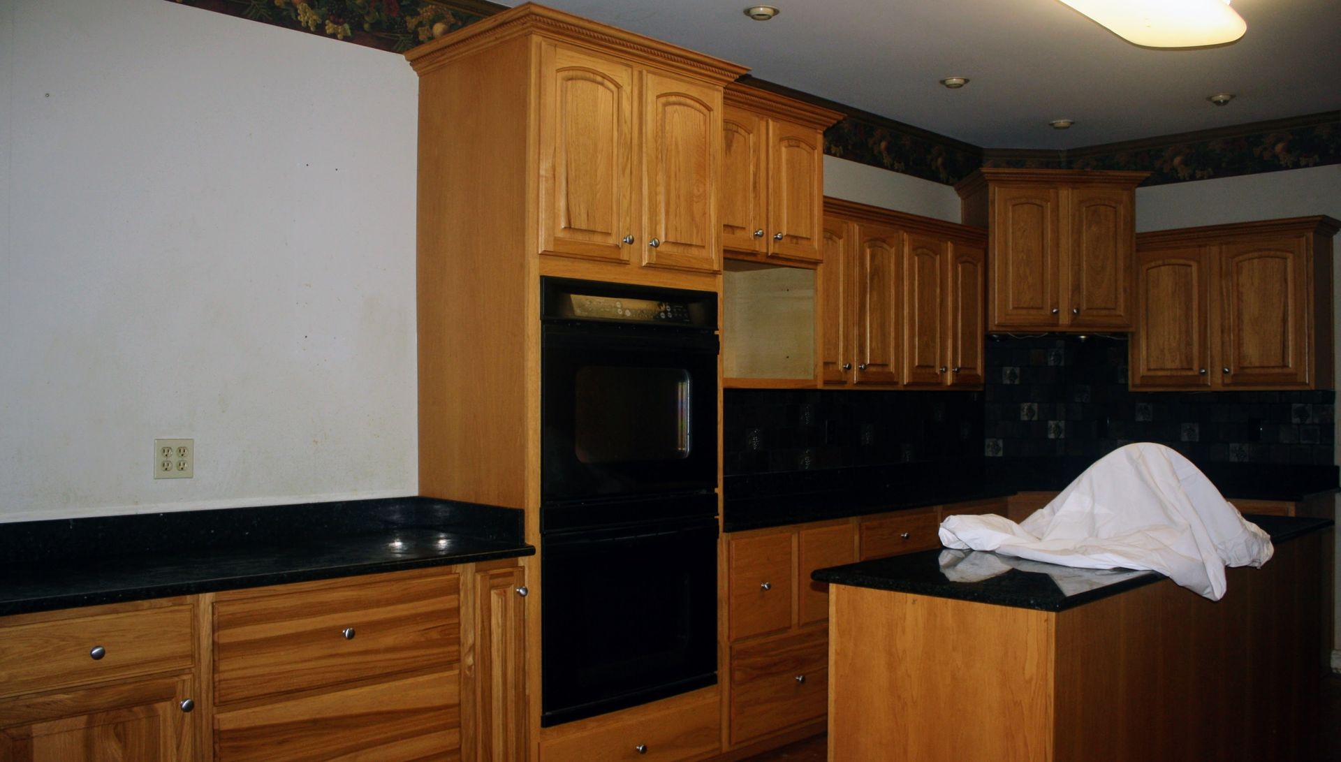 A kitchen with wooden cabinets and black counter tops