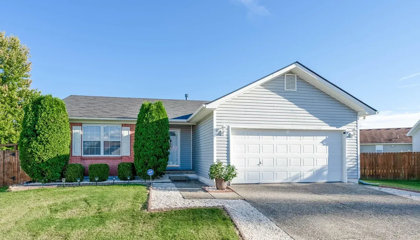 A white house with a red door and a white garage door.