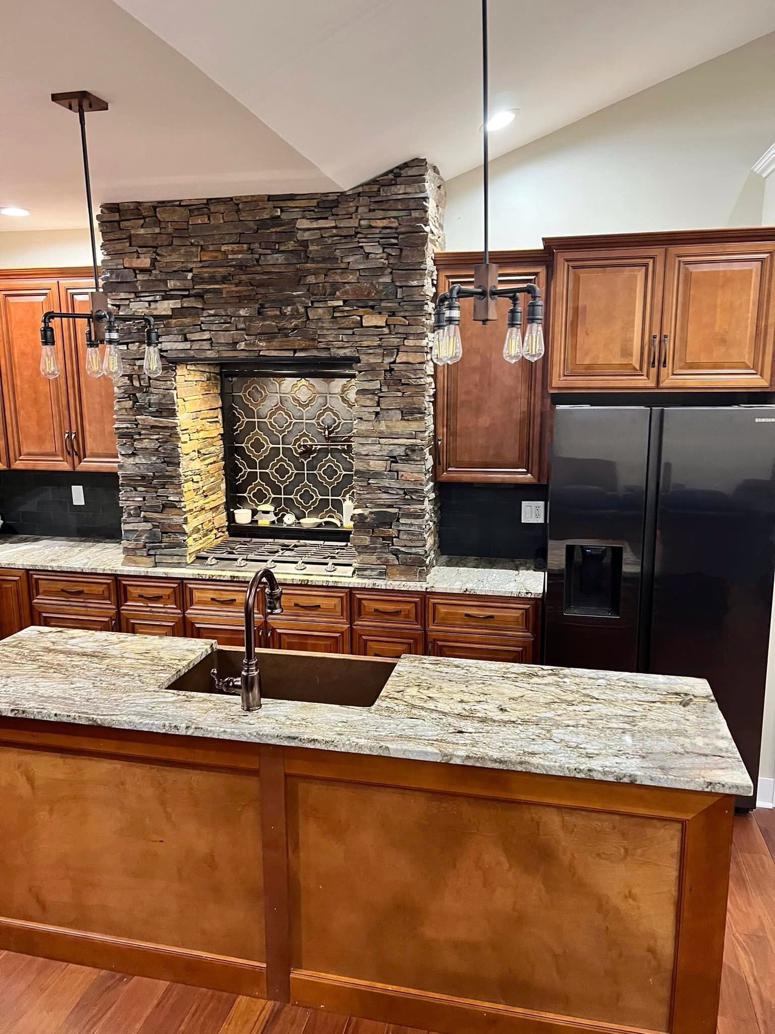A kitchen with granite counter tops , a sink , and a stone wall.
