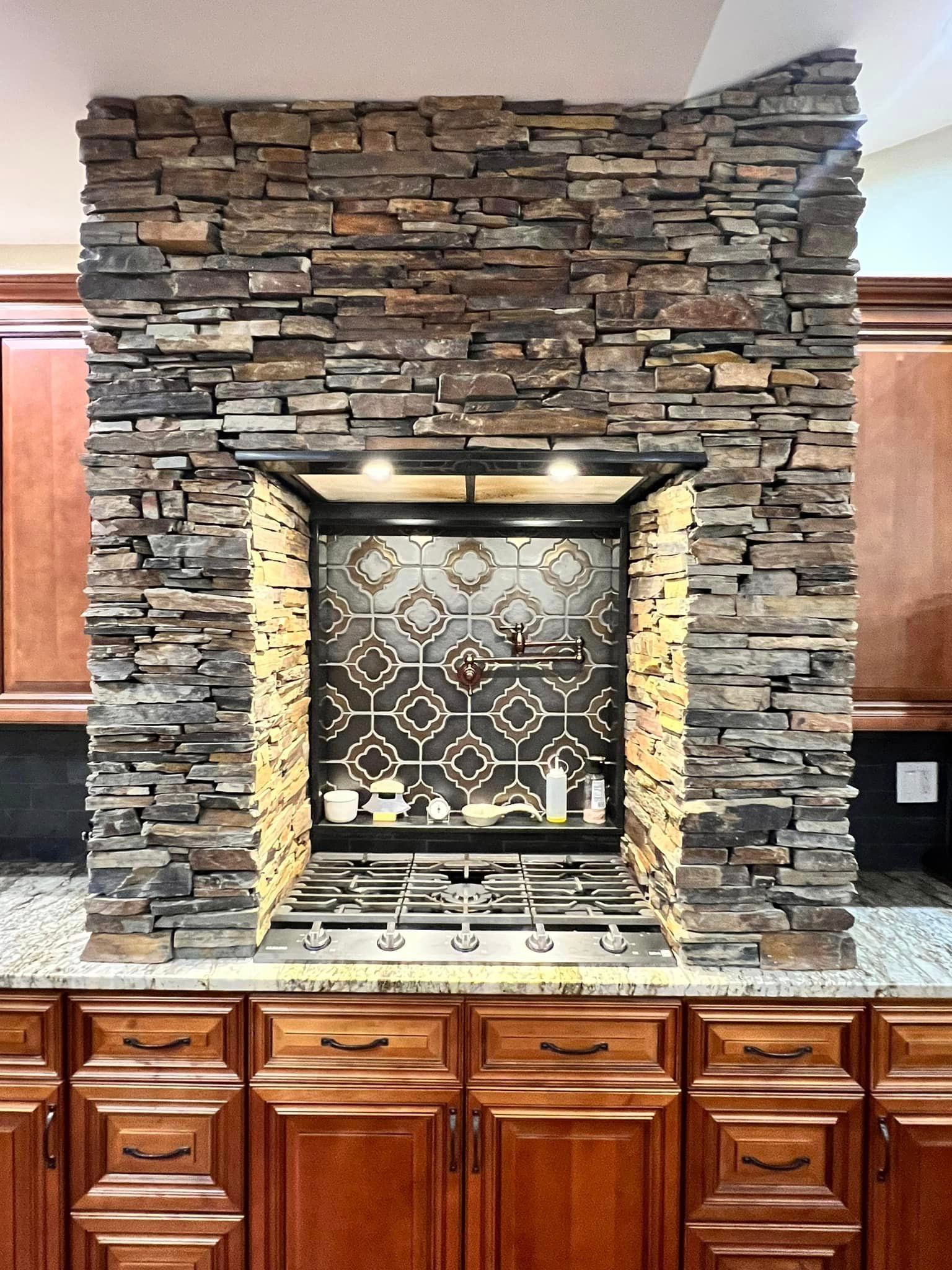 A kitchen with a stove and a stone wall behind it.