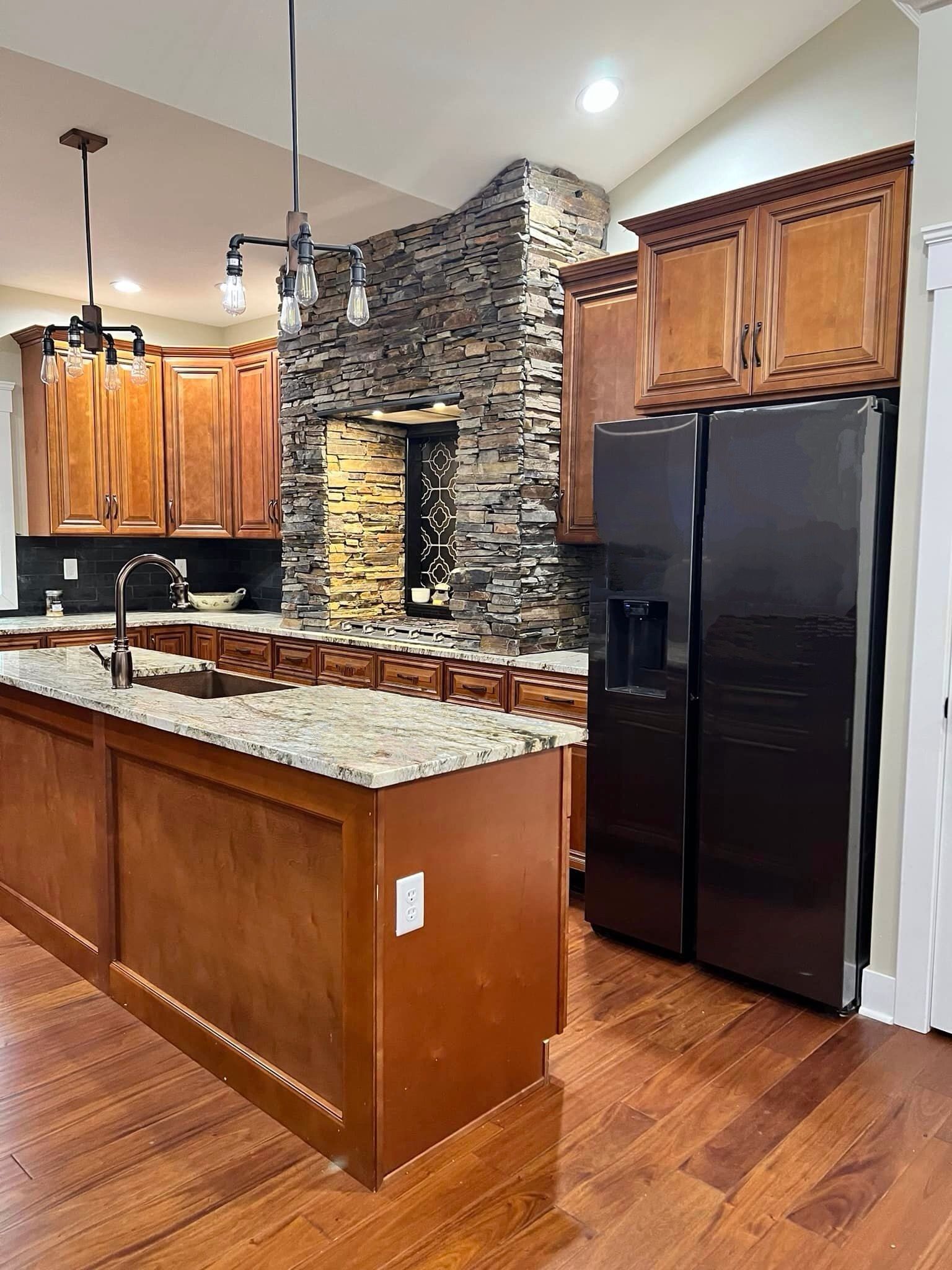 A kitchen with a large island and a black refrigerator