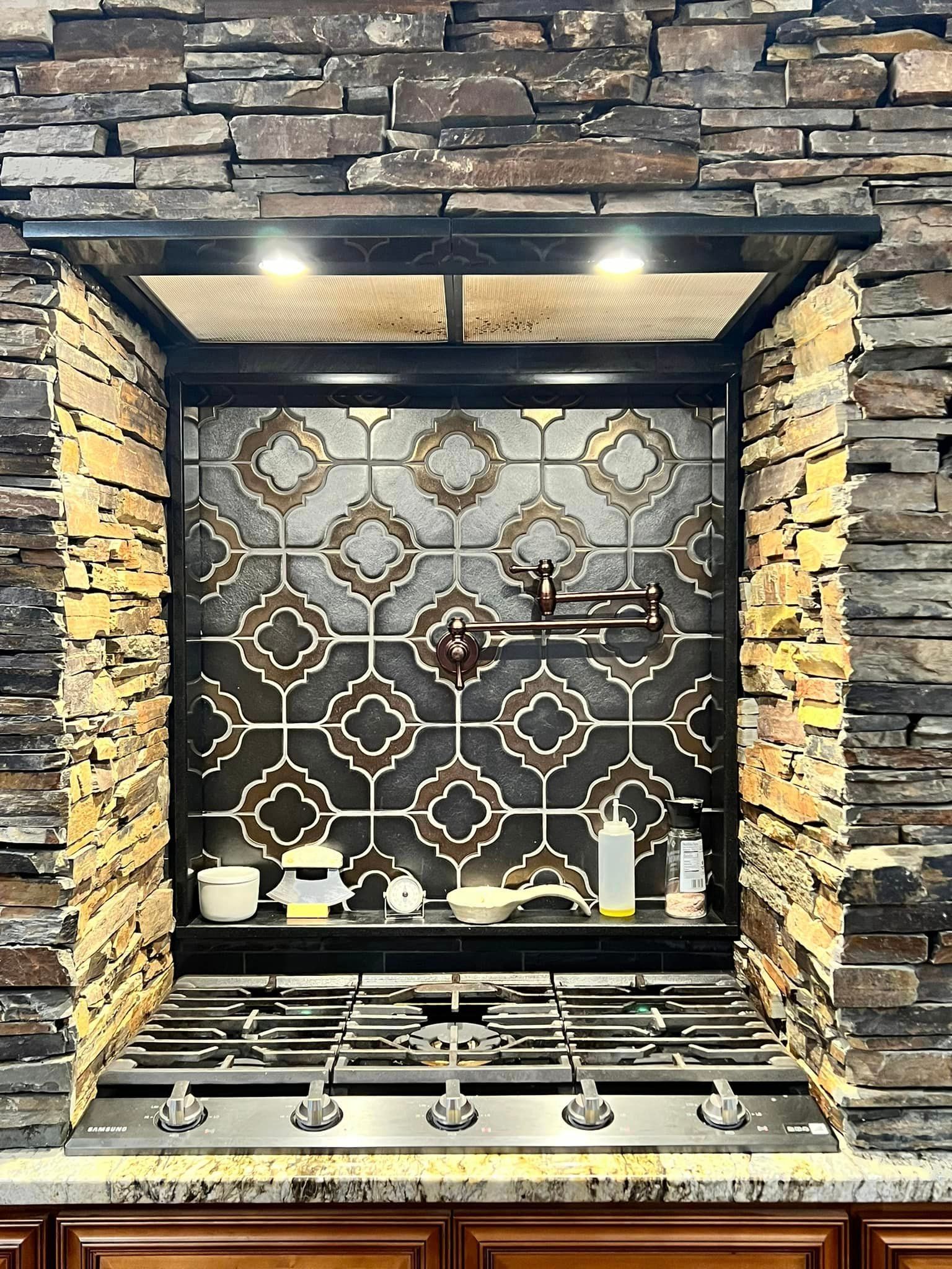 A kitchen with a stove and a brick wall behind it.