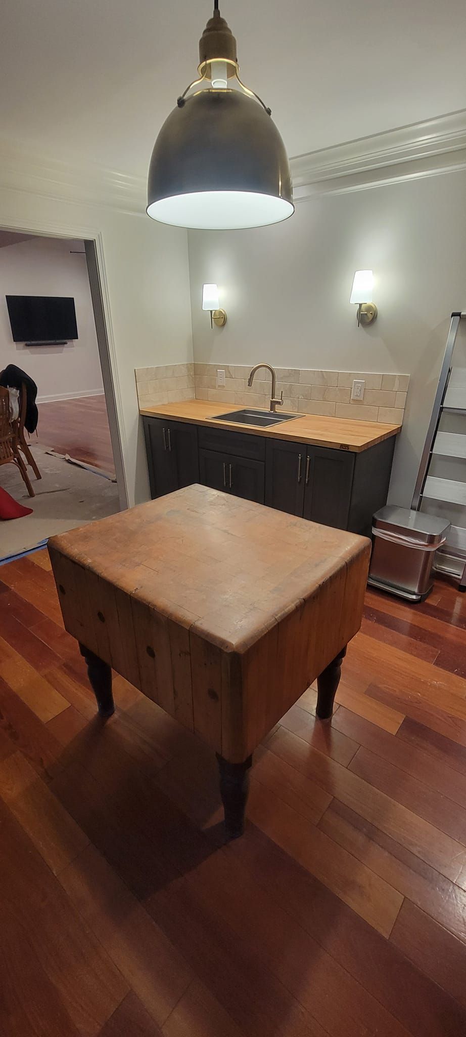 A wooden table is sitting in a kitchen next to a sink.