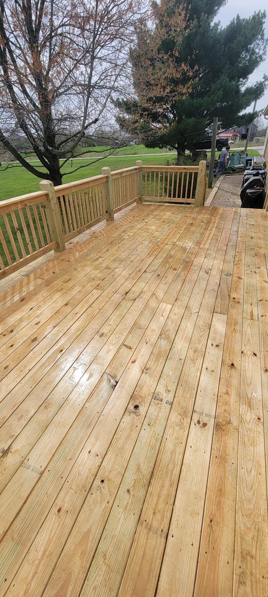 A wooden deck with a fence and trees in the background.