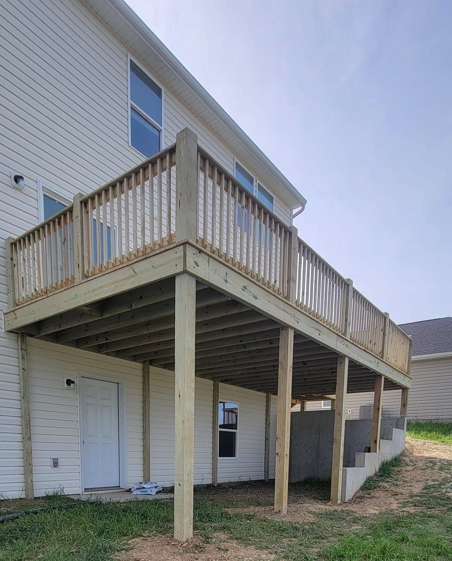 A white house with a large wooden deck in front of it.