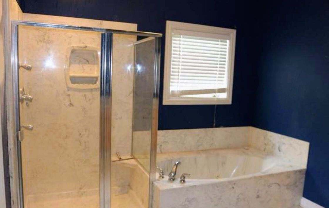 A bathroom with a tub , shower , and window.