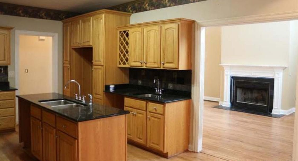 A kitchen with wooden cabinets , granite counter tops , a sink and a fireplace.