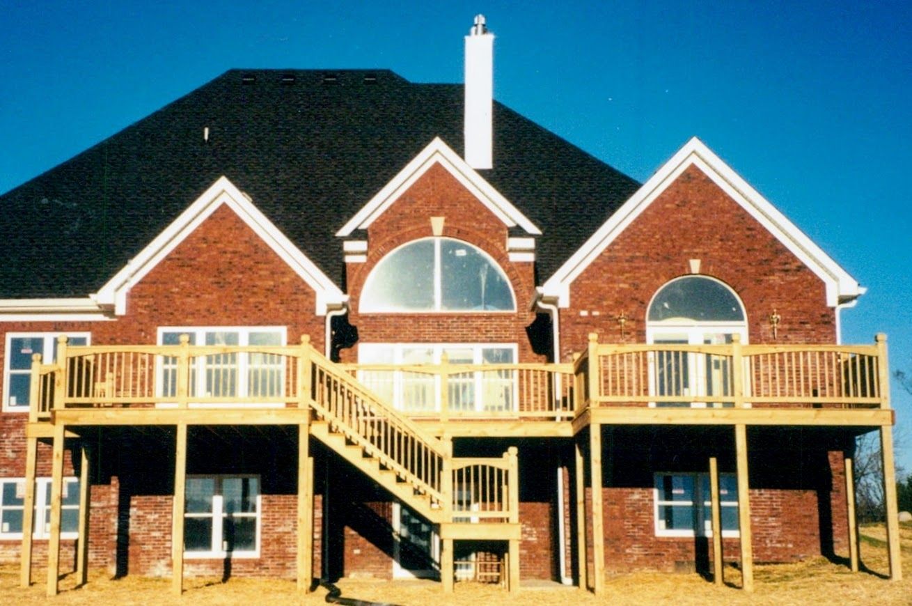 A large brick house with a wooden deck and stairs