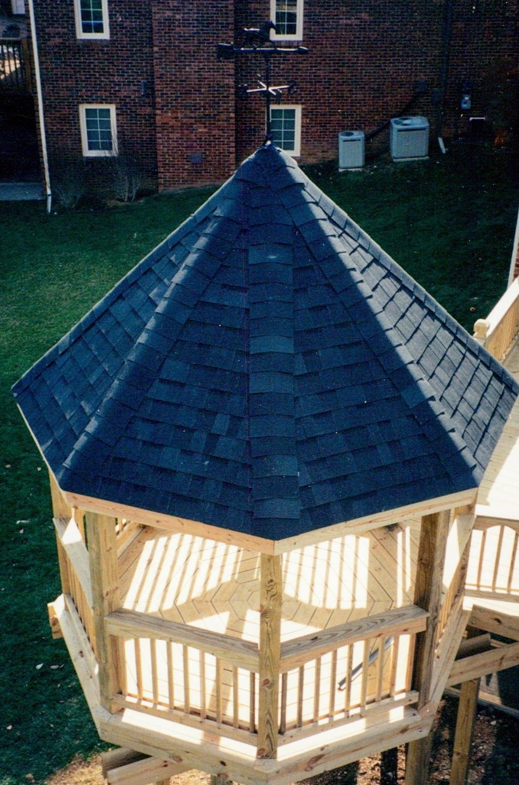 A gazebo with a blue roof and a brick building in the background