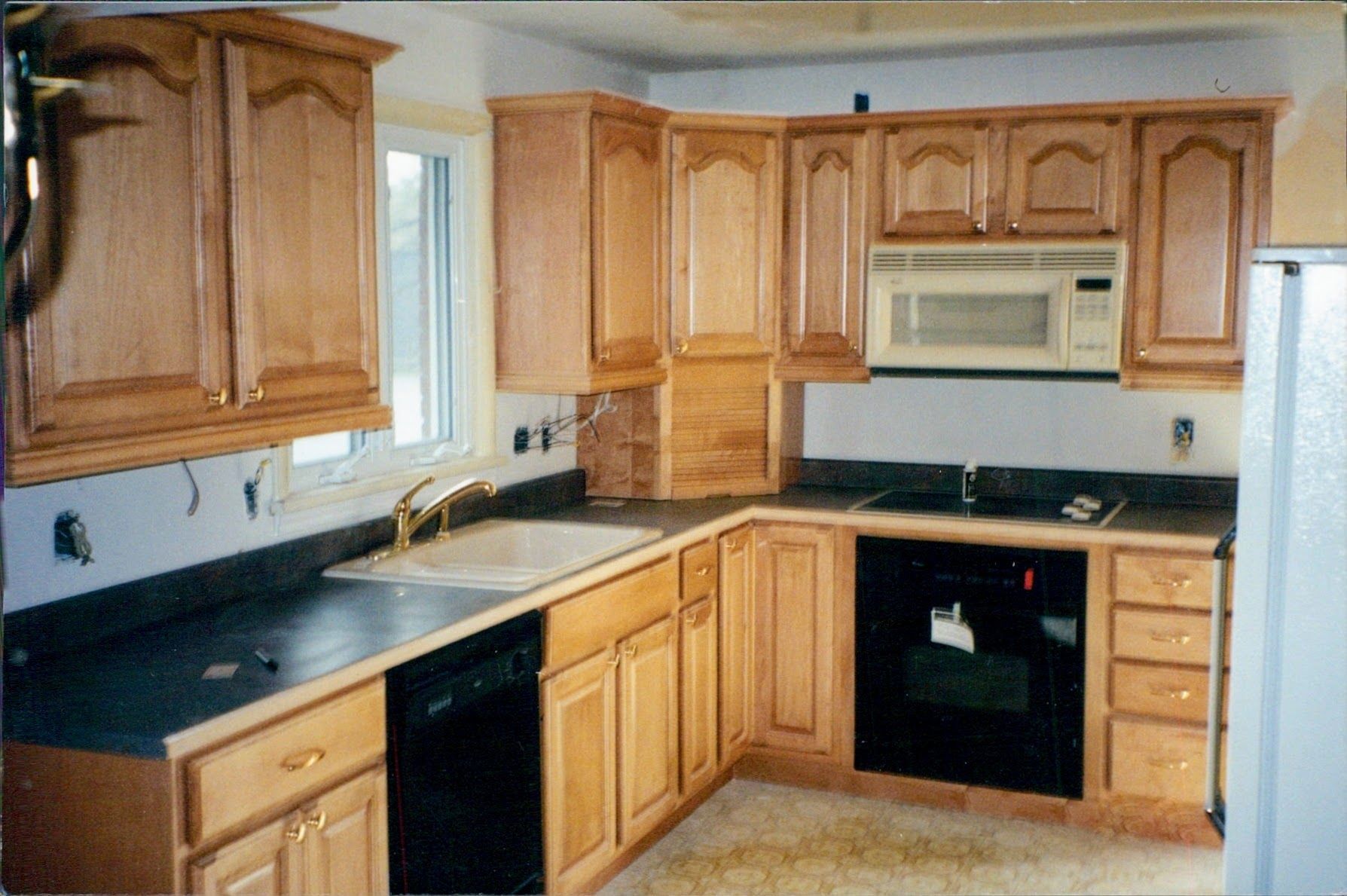 A kitchen with wooden cabinets and black counter tops