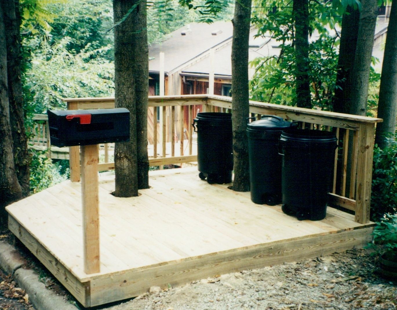A wooden deck with trash cans and a mailbox
