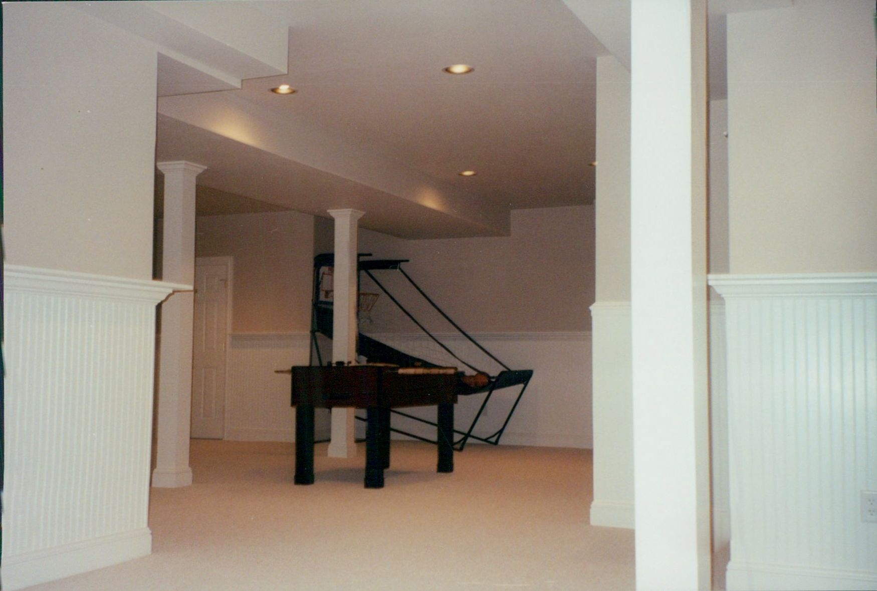 An empty basement with a pool table and stairs