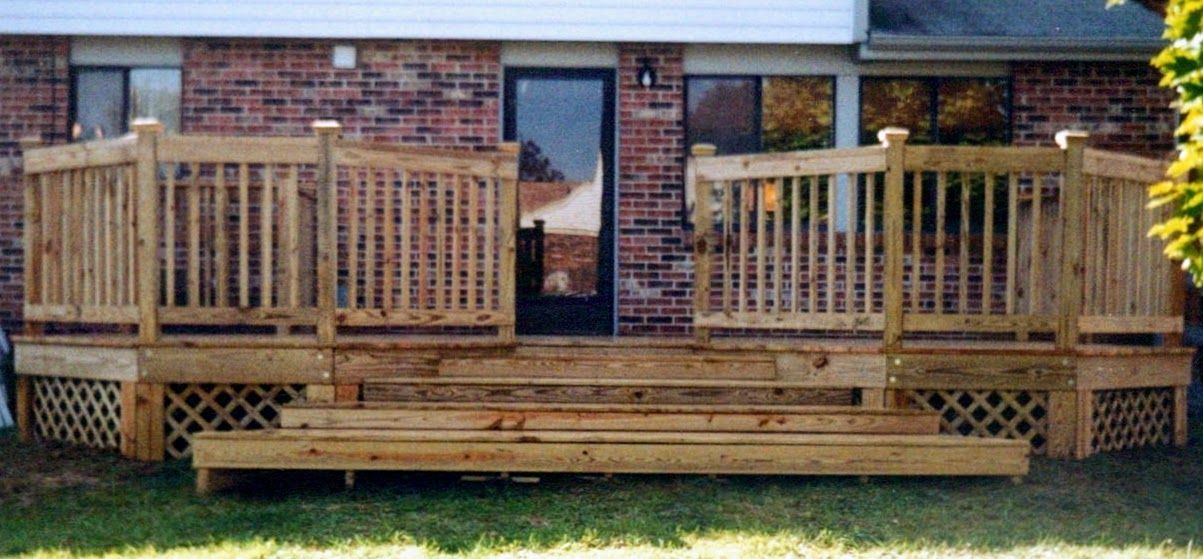 A wooden deck is in front of a brick house.