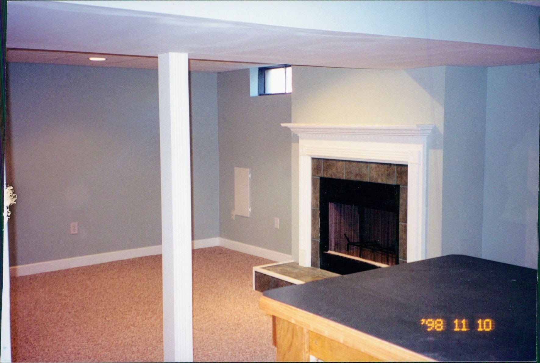 A photo of a basement with a fireplace taken in 1990