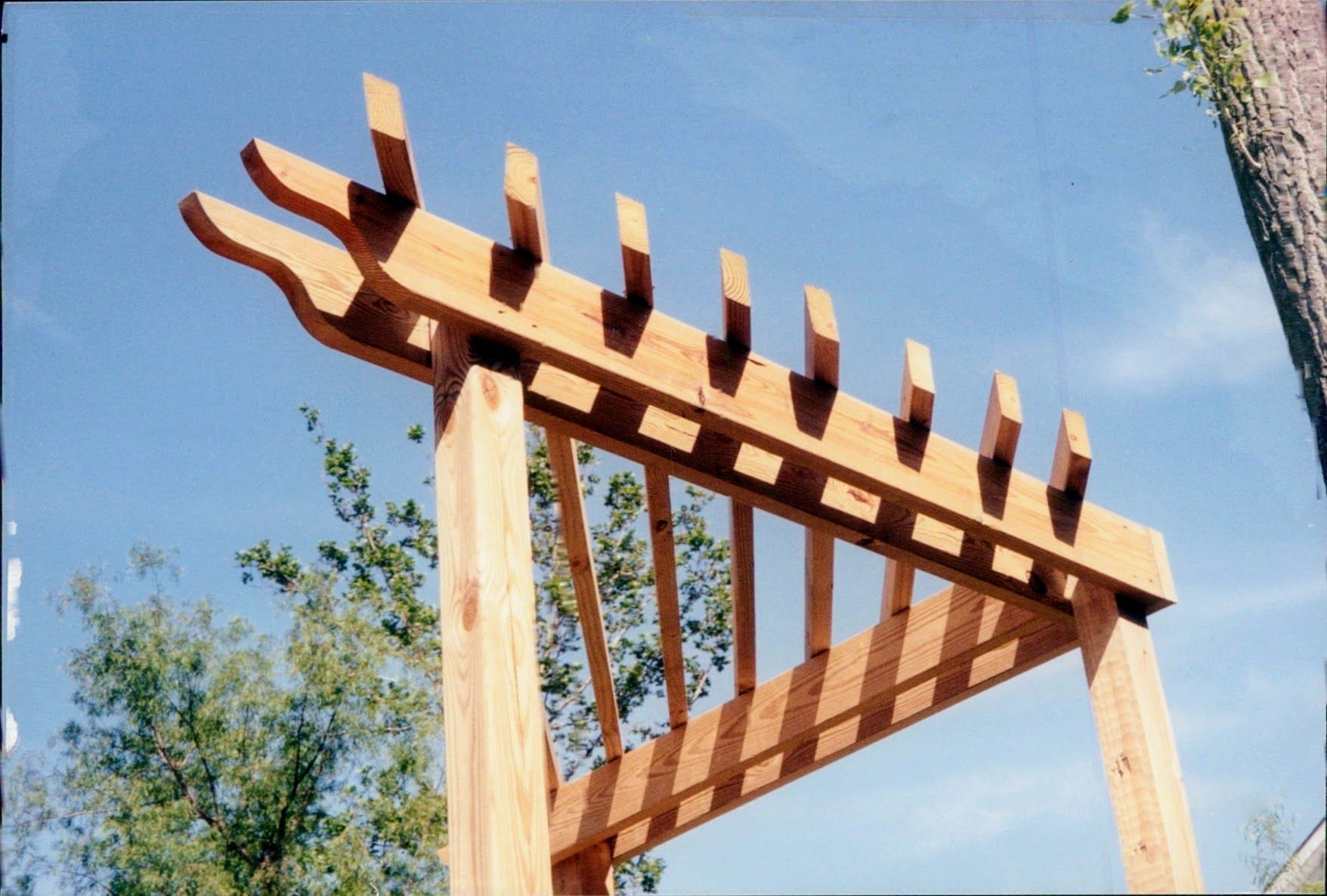 A wooden pergola with a blue sky in the background