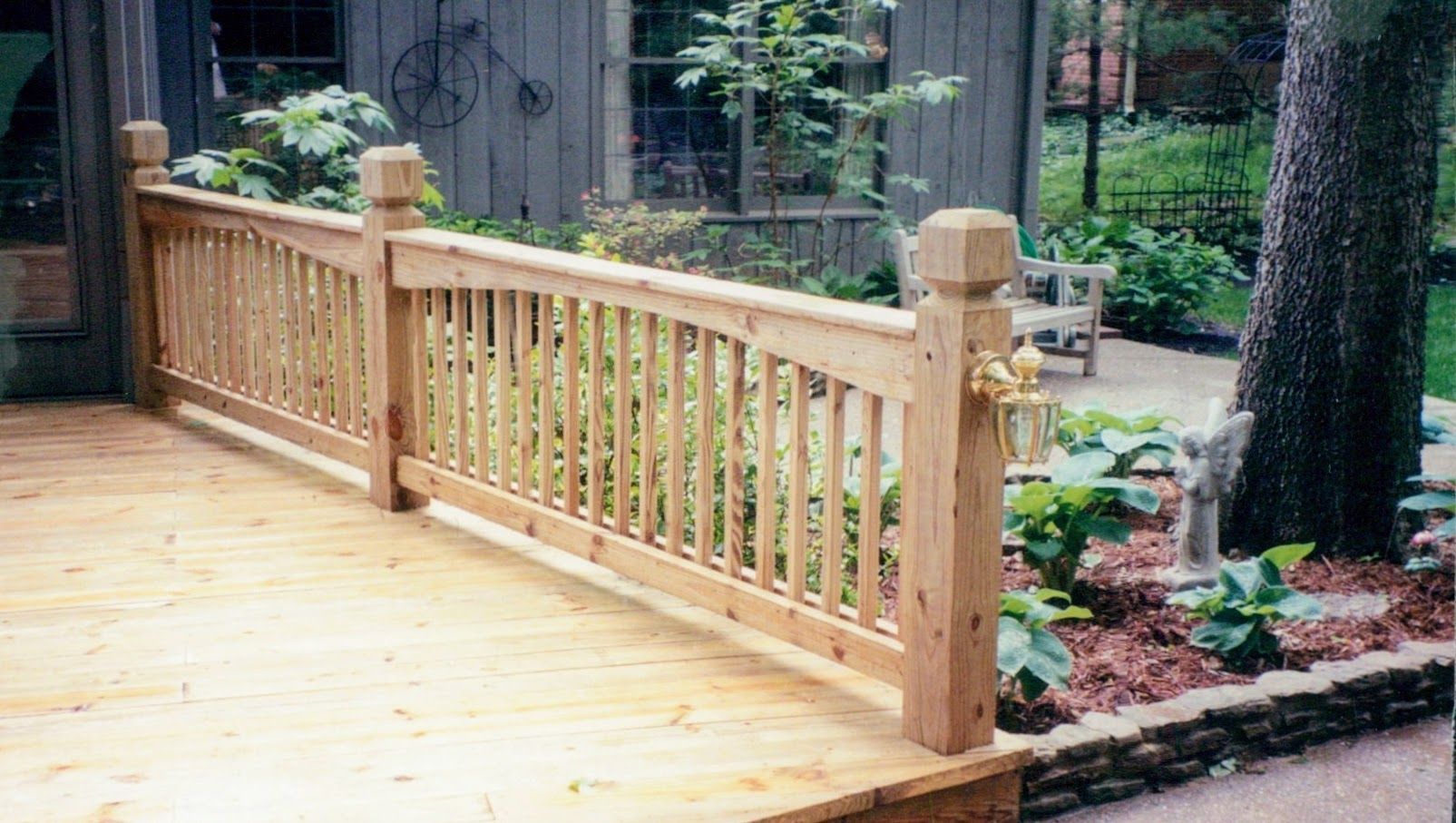 A wooden fence surrounds a wooden deck in a backyard.