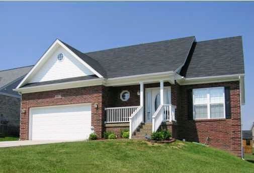 A brick house with a black roof and a white garage door