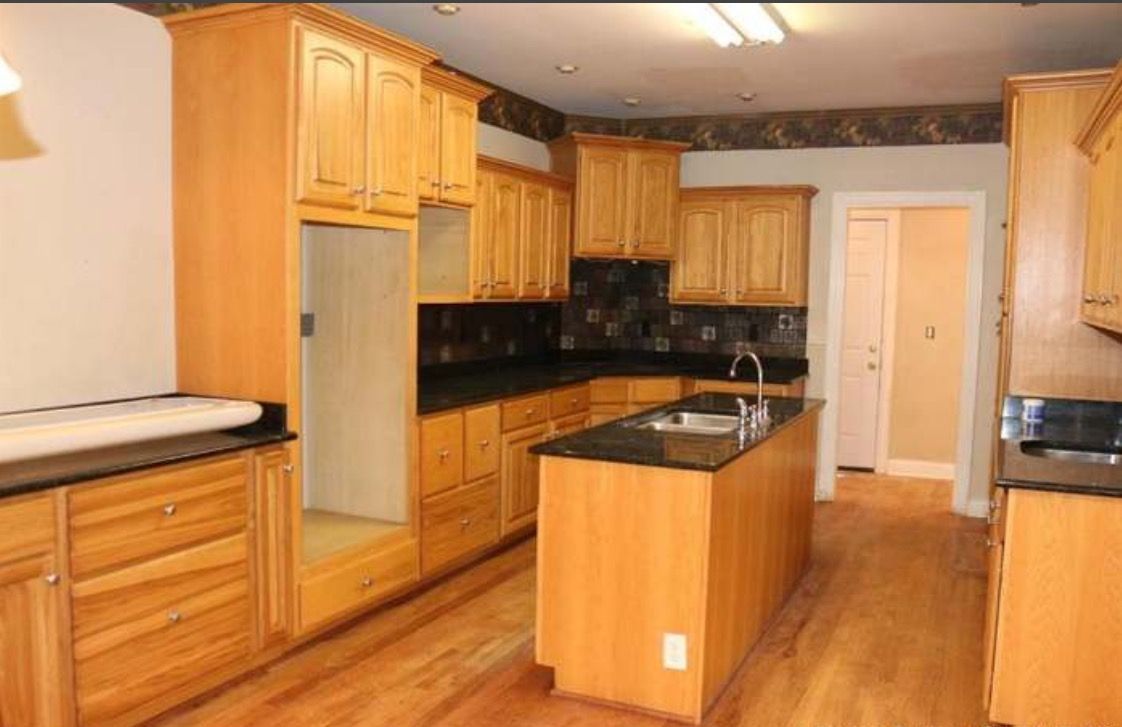 A kitchen with wooden cabinets and black counter tops