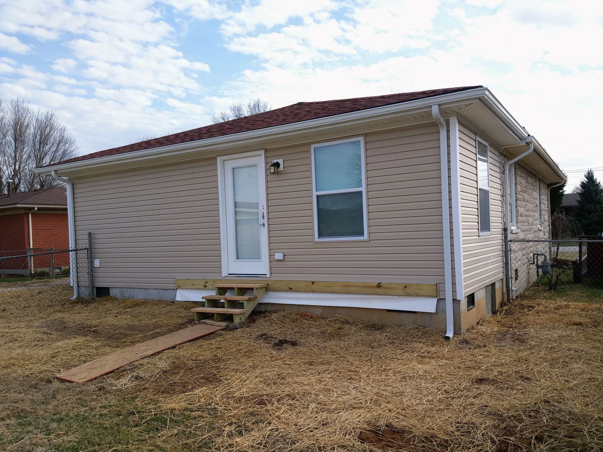 A small house with a red roof is sitting in the middle of a field.