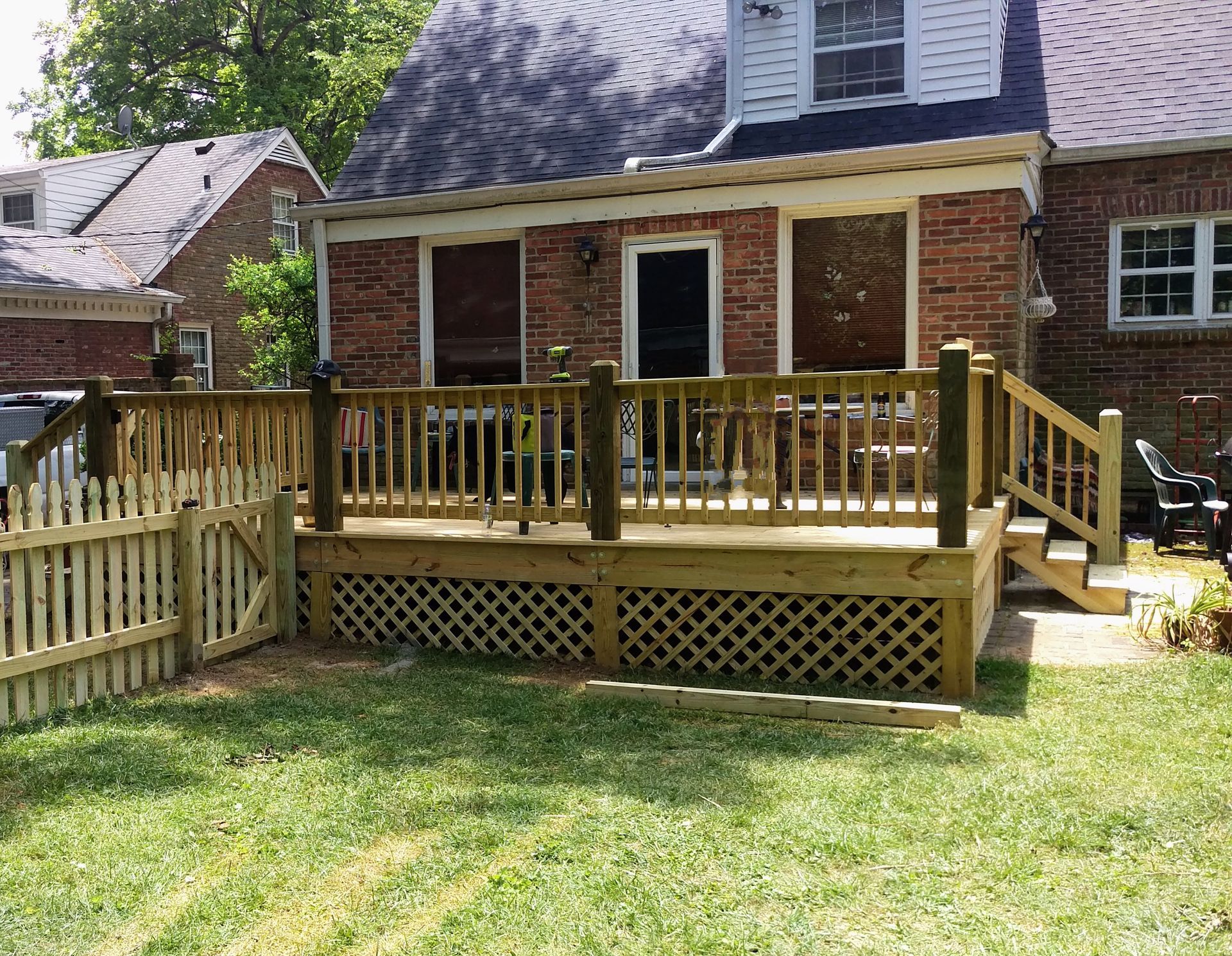 A wooden deck is sitting in front of a brick house.