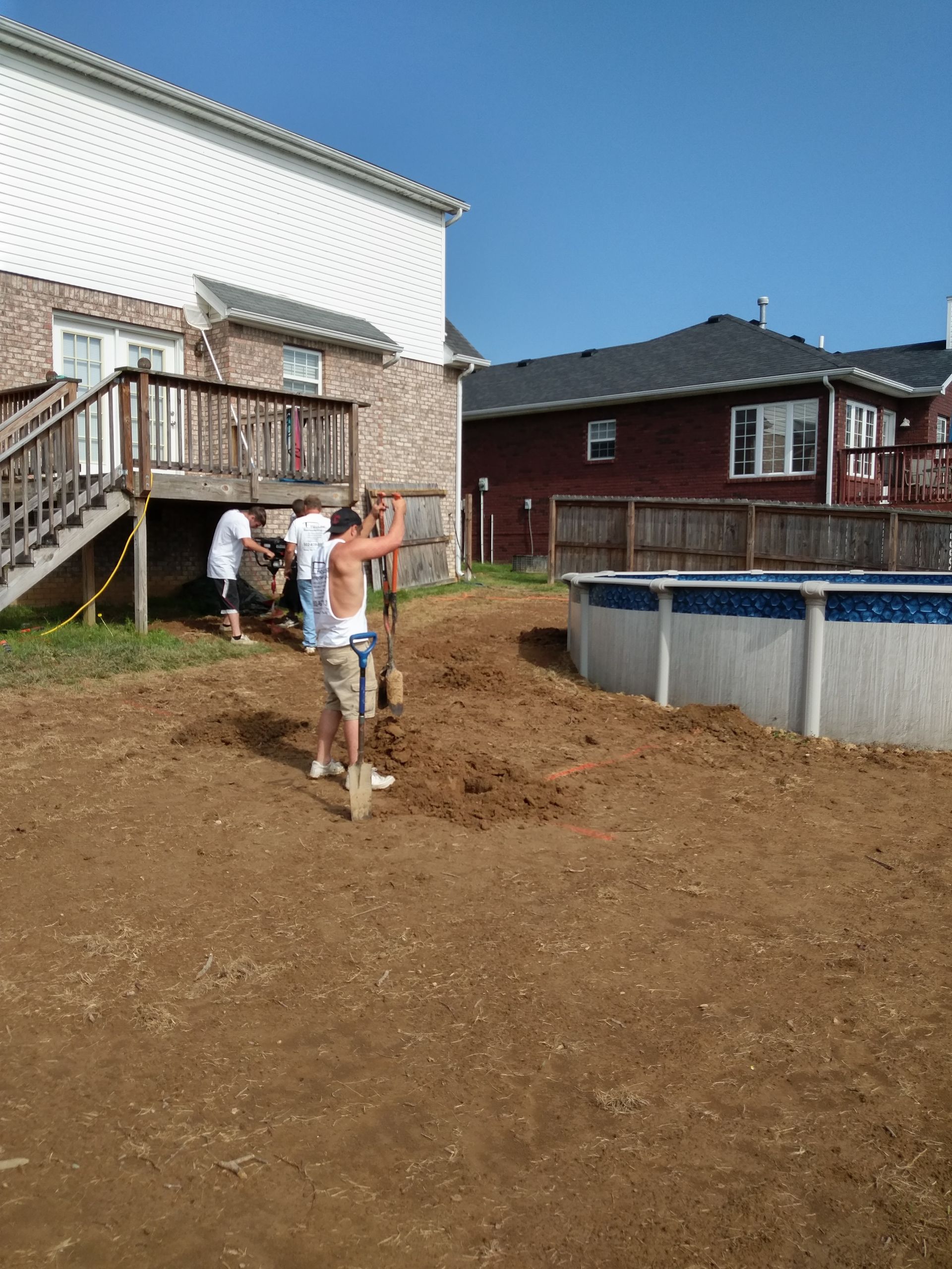 A group of people are working in a backyard near a pool