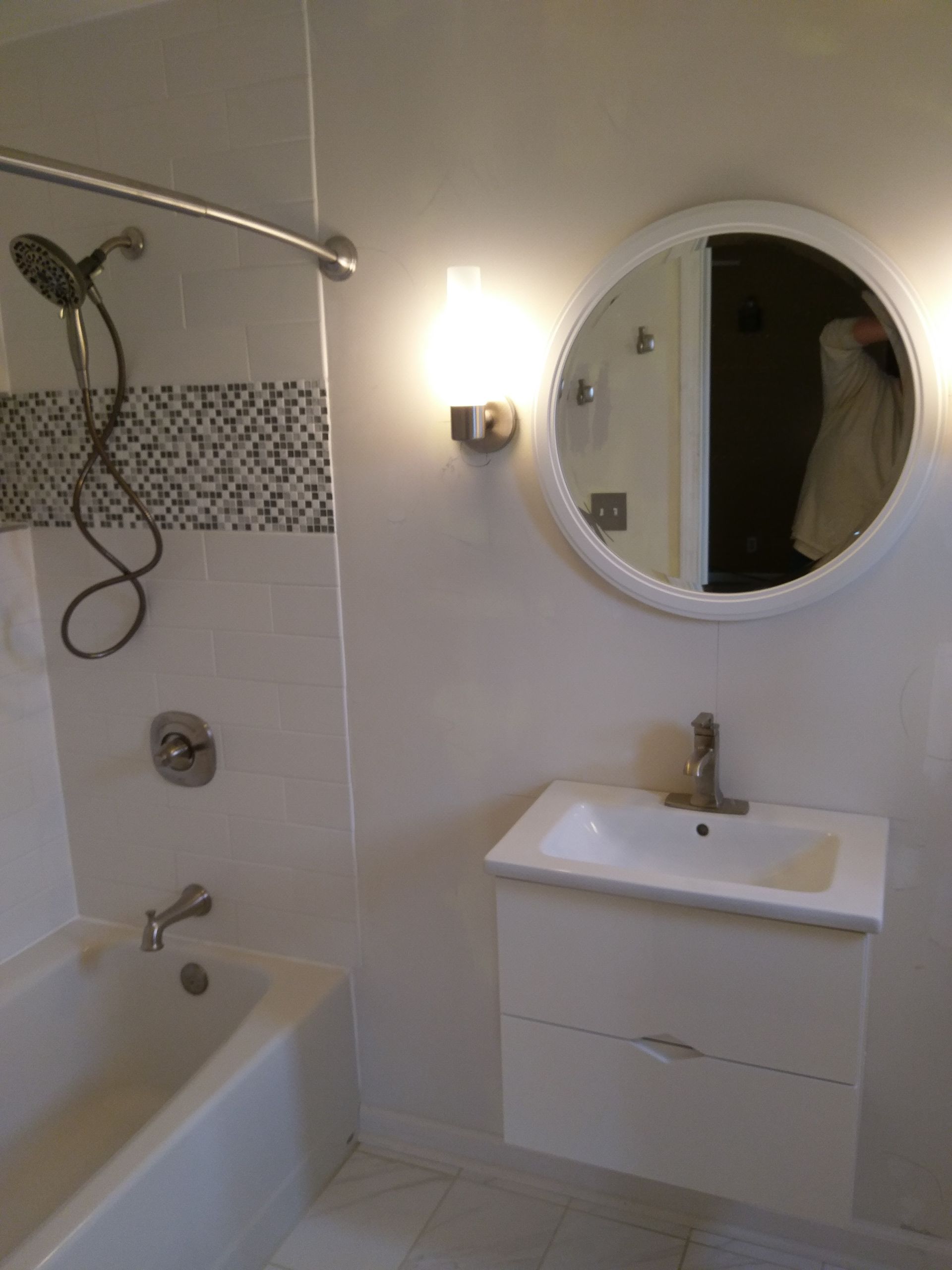 A bathroom with a sink and a round mirror