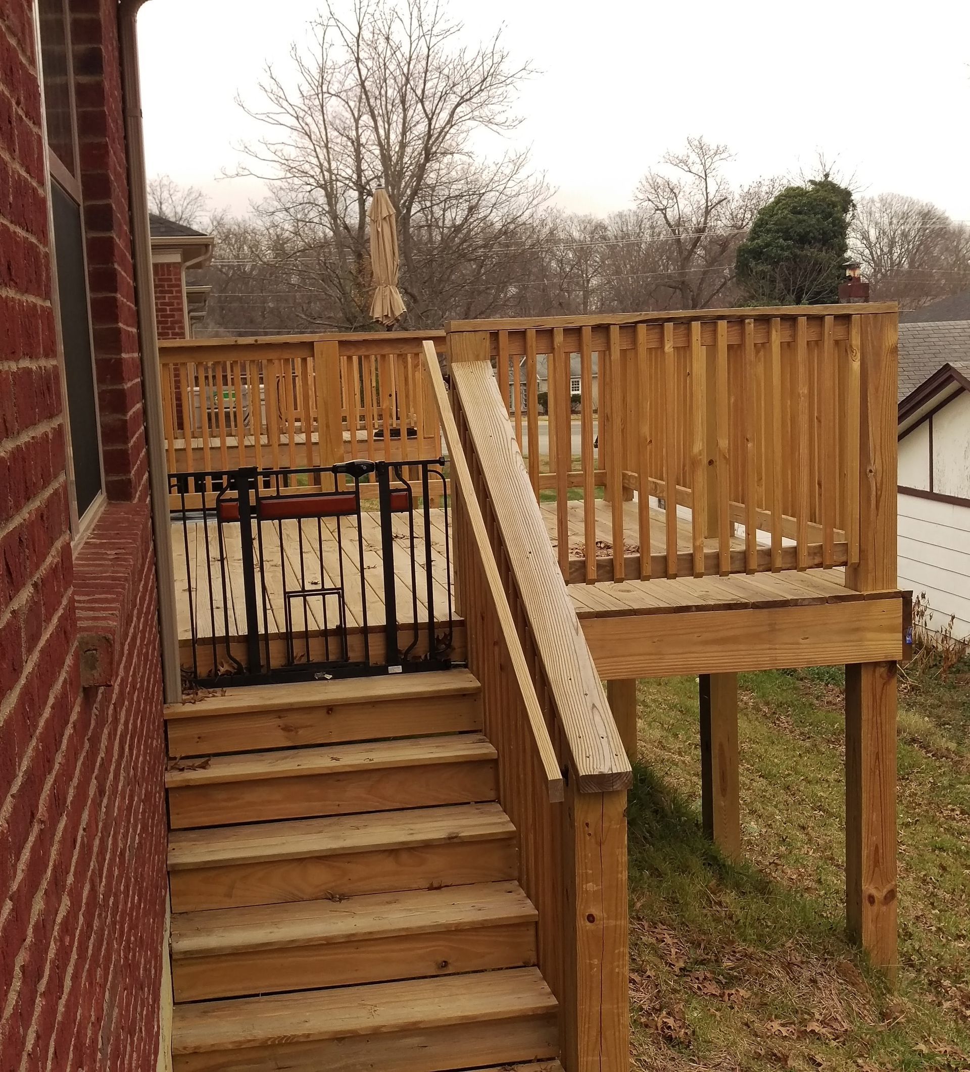 A wooden deck with stairs leading up to it is next to a brick building.