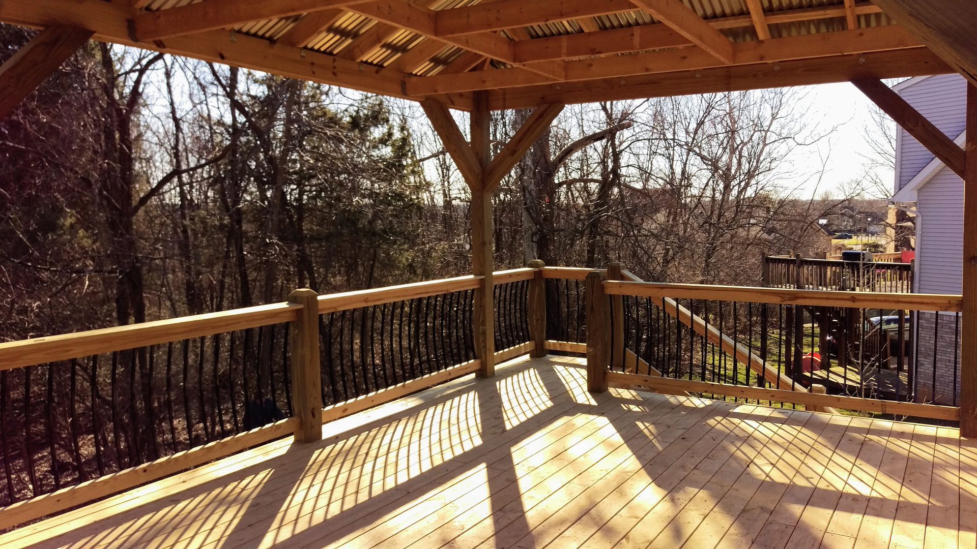 A wooden deck with a gazebo and trees in the background