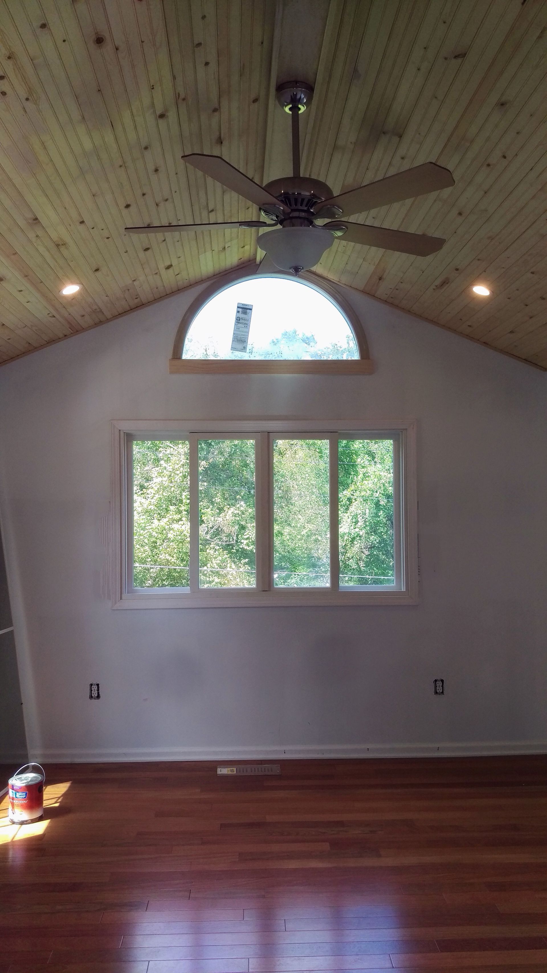 An empty room with a ceiling fan and a window.
