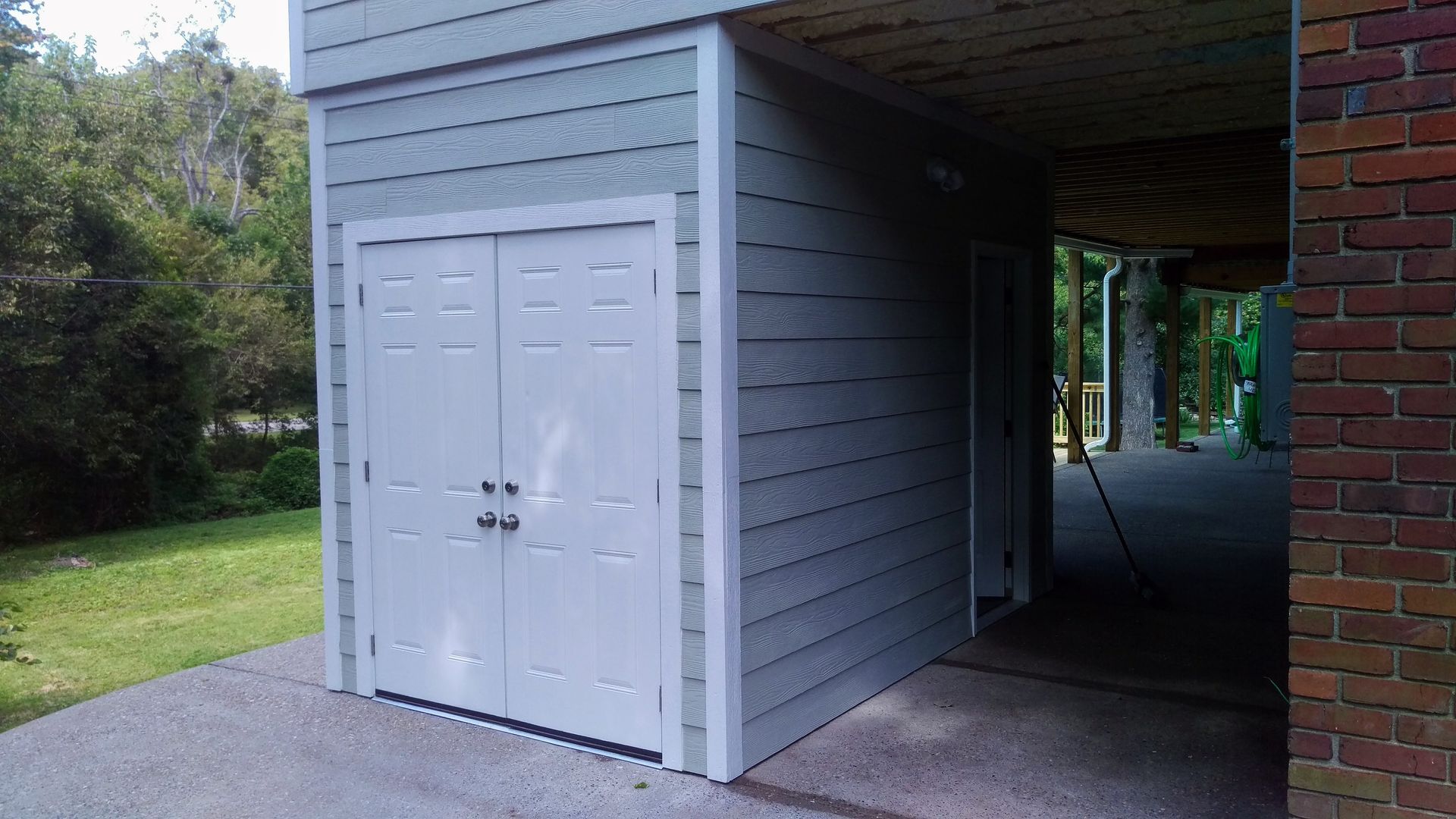 A white garage with a brick building in the background