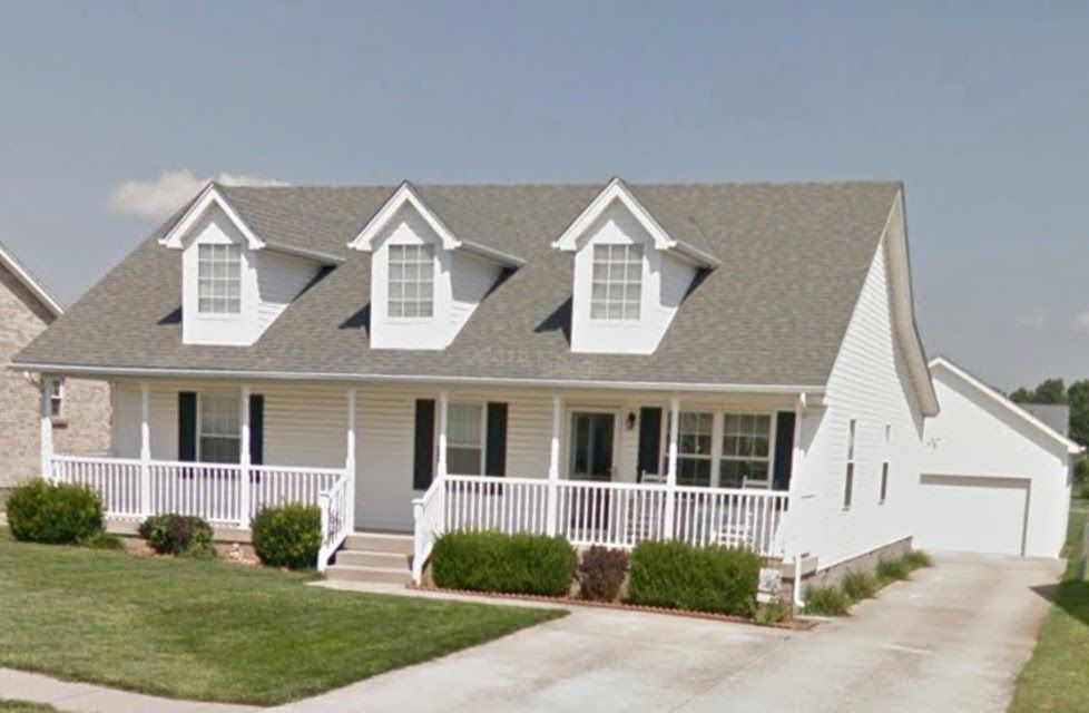 A white house with a gray roof and a porch