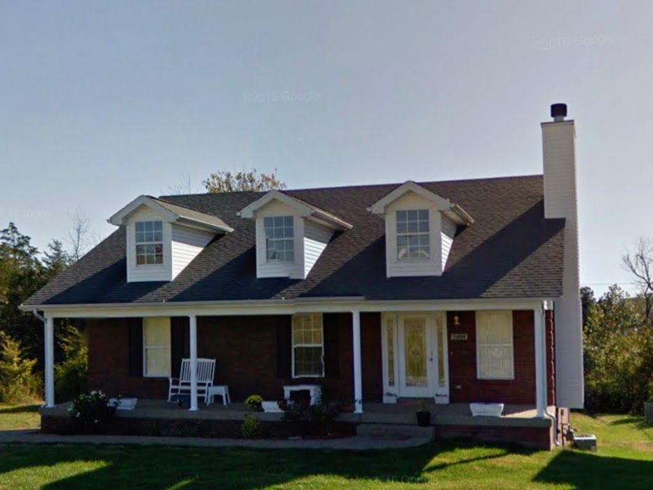 A brick house with a porch and a chimney