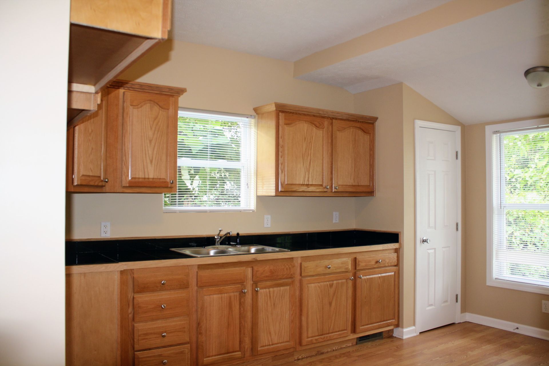 An empty kitchen with wooden cabinets and a sink