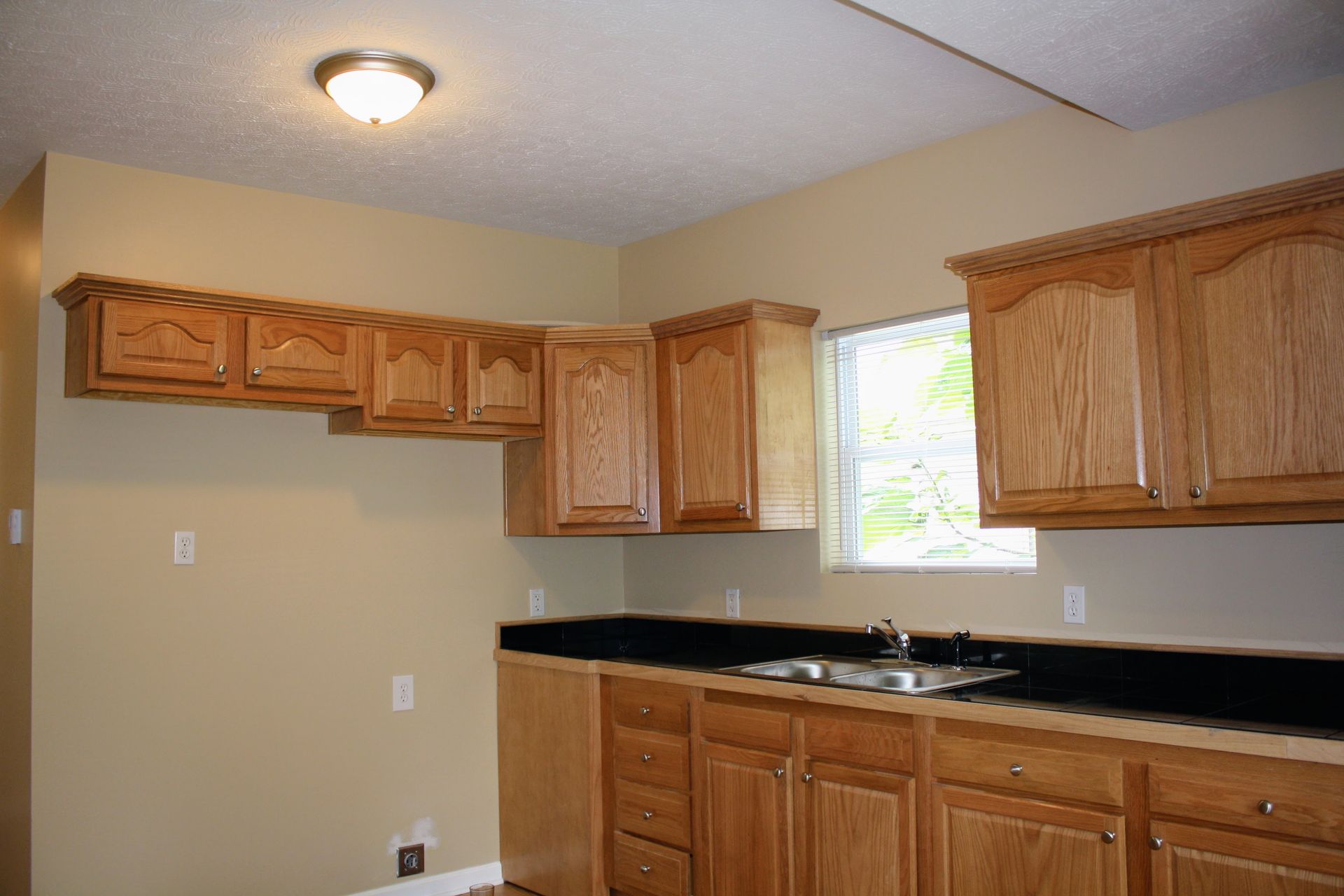 An empty kitchen with wooden cabinets and a sink