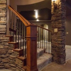 A staircase with a wooden railing and a stone wall
