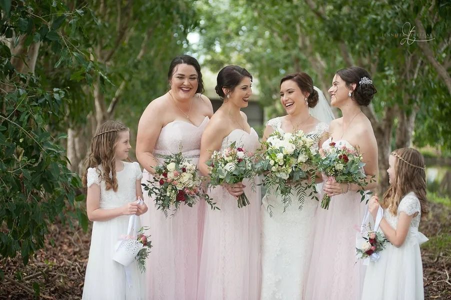 Bride and Bridesmaids in Blush Pink Dresses With Flower Girls Holding Bouquets — Villa Lamor in Balberra, QLD