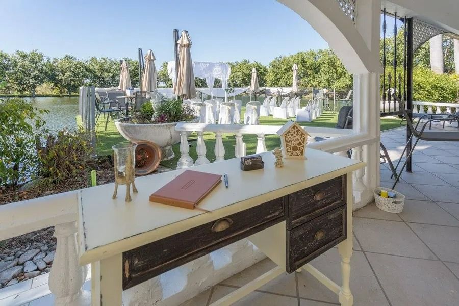 Desk on Patio Overlooking a Lake, With Decor Items Like a Notebook and Birdhouse — Villa Lamor in Balberra, QLD