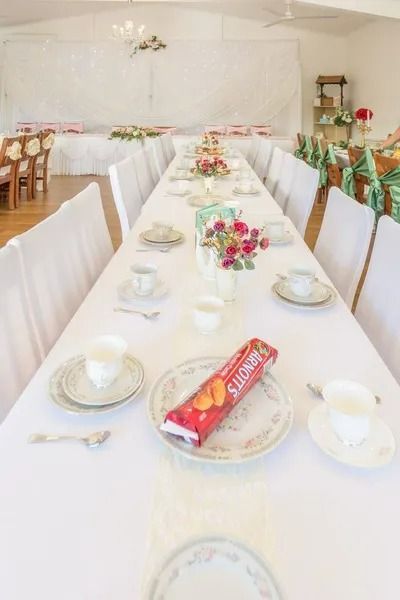 Long Table Set for Tea With White Linens, Floral Centerpieces, and Place Settings — Villa Lamor in Balberra, QLD