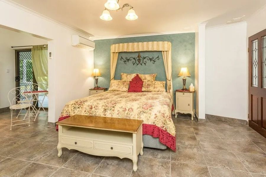 Bedroom With Floral Bedding, Canopy Headboard, Lamps, and a Wooden Bench — Villa Lamor in Balberra, QLD
